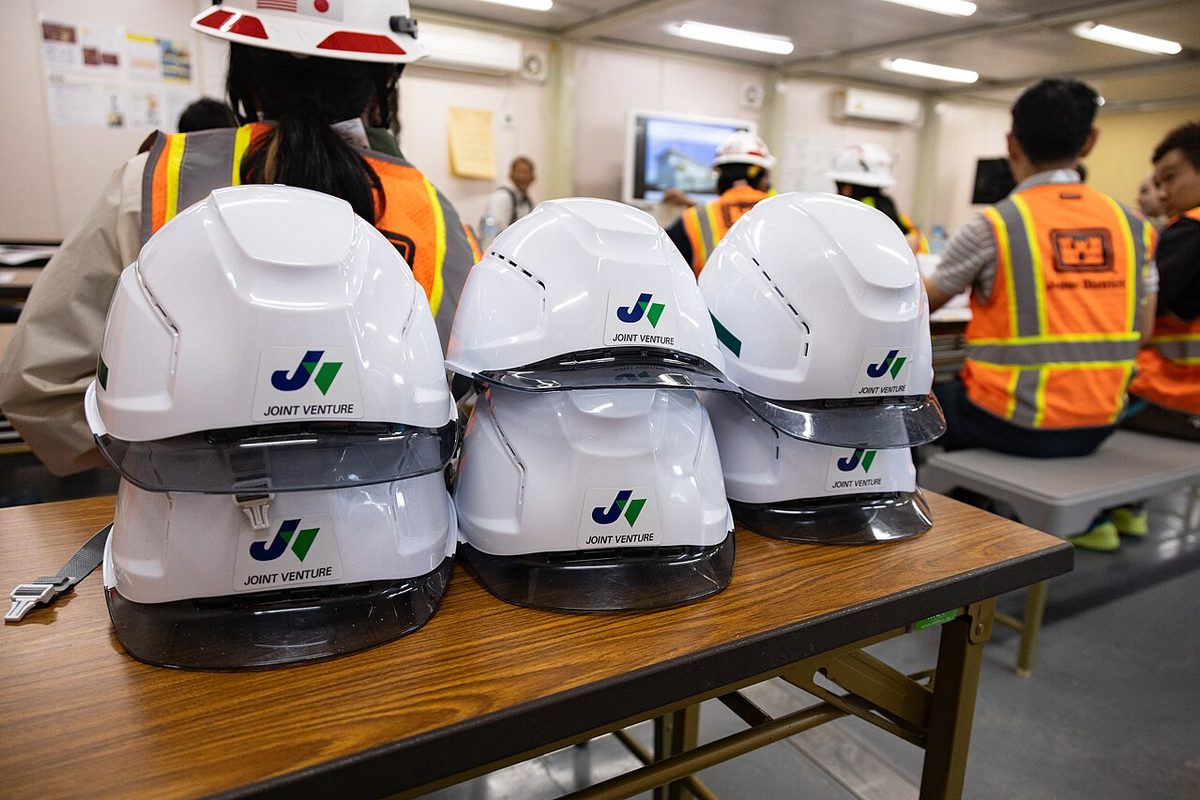 Cascos blancos de ingeniería y equipo de trabajo en una obra